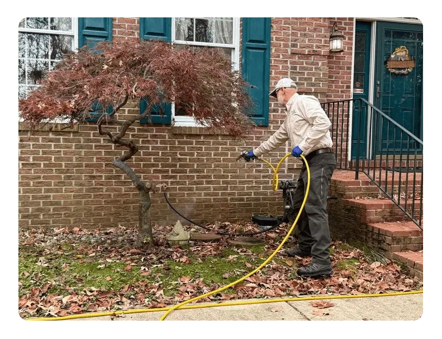 A Planet Friendly Pest Control technician treating a home's exterior perimeter